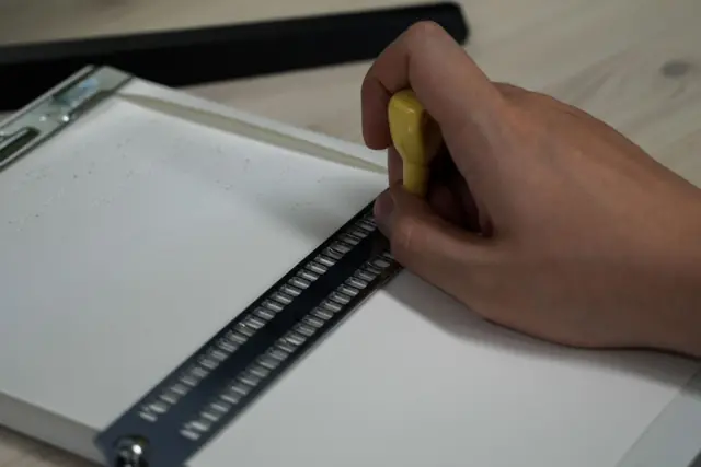 점판에 종이를 끼우고 작은 송곳처럼 생긴 점핀으로 점자를 찍는 손