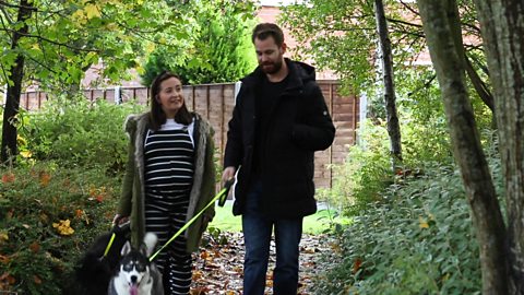 Pregnant woman dog walking with her partner.