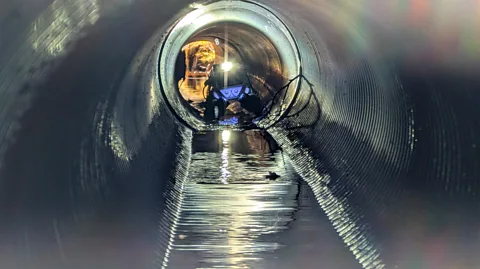 Pipeon project An autonomous inspection robot at one end of a long sewer pipe with water running along the bottom section (Credit: Pipeon project)