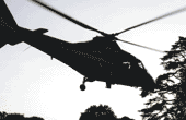 silhouette of a helicoptor flying over some trees