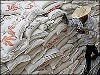 Homem anda ao lado de sacas de arroz